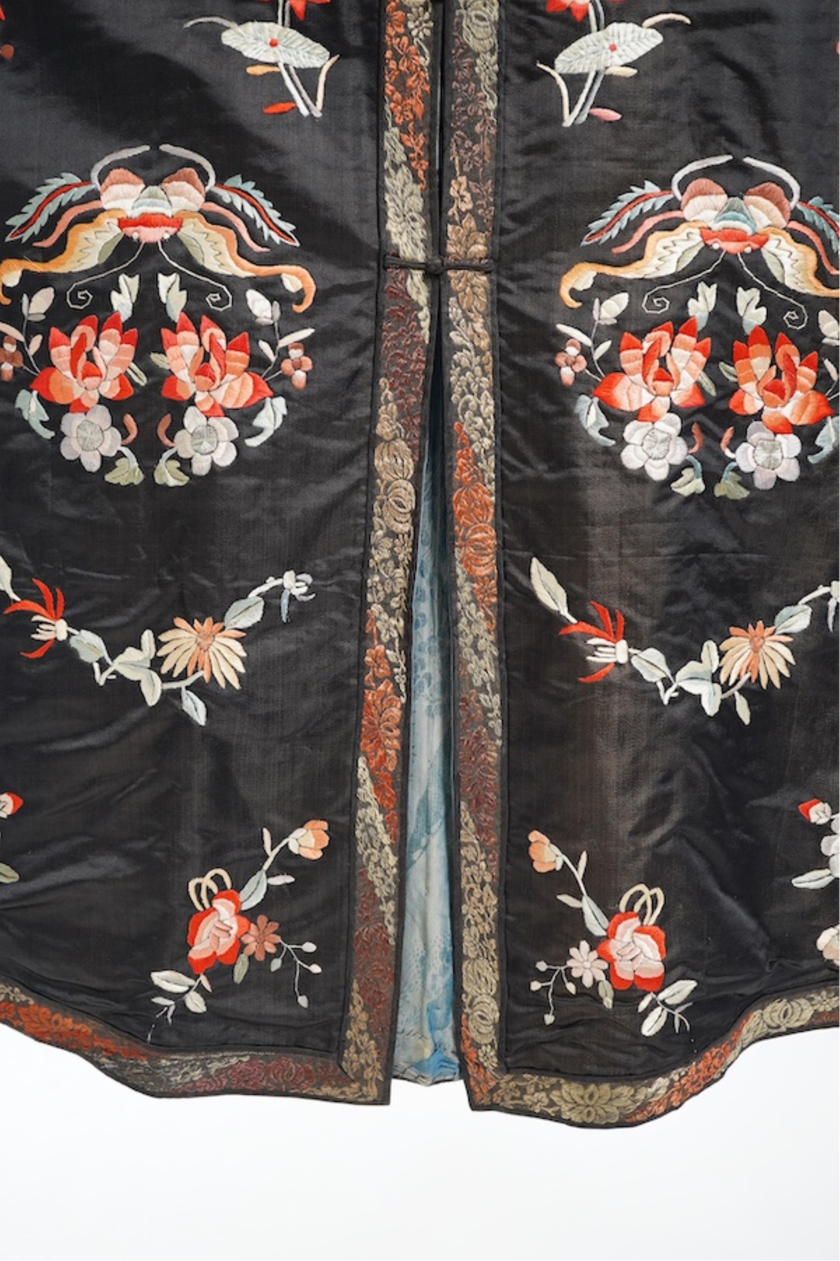 A late 19th early 20th century Chinese black silk polychrome embroidered ladies robe, decorated with cream silk, gilt and Peking knot bordered sleeve bands. The sleeve bands worked with fine figural and other embroidered